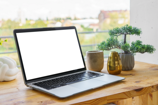 Laptop computer with white, transparent screen on wooden desk on wide window background. Office workspace, workplace in cafe or home. Mockup, template with copy space