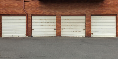 four metal tilt-up canopy garage doors in a row against red brick building in Sydney, Australia