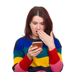 Surprised young woman covers her open mouth with hand while browsing her phone. Wow portrait of amazed girl. Stunned and shocked female emotion