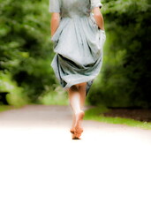 A person in a dress is running barefoot on a path.
