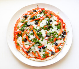 round pizza with olives, pepper, mozzarella, dill and pork on a round plate, top view