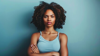 Thoughtful young African-American woman with crossed arms looking at camera.