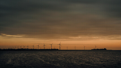 Panoramabild - Eine lange Reihe von Windrädern an der Küste des IJsselmeeres bei Sonnenuntergang