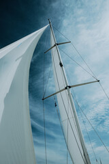 Imagebild Segeln - Close Up vom Mast einer Segelyacht mit gehisstem Segel vor dramatisch blauem Himmel, IJsselmeer, Niederlande