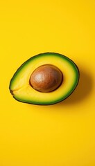 Ripe avocado halved on vibrant yellow background, vegan, mineral, smooth