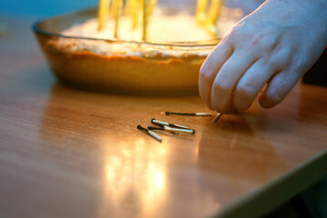 Burnt wooden matches arranged by hand near a festive cake with candle remnants, capturing a celebratory moment