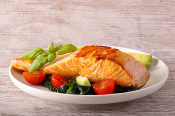 Salmon with spinach and tomato on plate