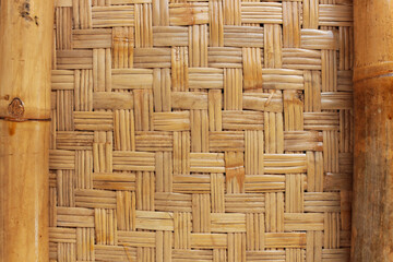 A detailed close-up of tightly woven bamboo, showcasing its intricate pattern and natural texture. The light brown and beige tones of the bamboo create a warm and earthy background.