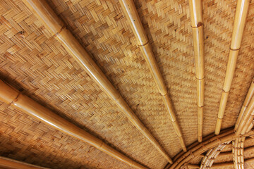 View of a woven bamboo roof or ceiling, showcasing the natural textures and warm tones of the bamboo material.