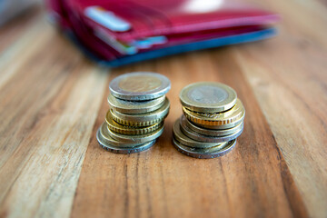 Metal coins stack. Money near the wallet on the wood table.
