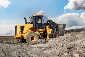A loader or bulldozer moves large rocks on a job site.