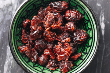 Dried cranberries in green bowl. Healthy sweet snack. Dark rustic marble background. Closeup macro...