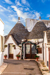 fancy beautiful buildings trulli with white old walls and strange roofs on a blue sky background of...
