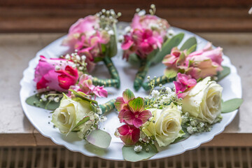 Small stylish boutonnieres on white marble plate, flat lay colorful many groom