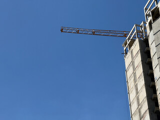 constructing of tall building, with crane to lift materials with blue sky on the background and space for copy or text, construction area