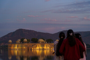Women watching over Jal Mahal with a beautful view of Pink clouds