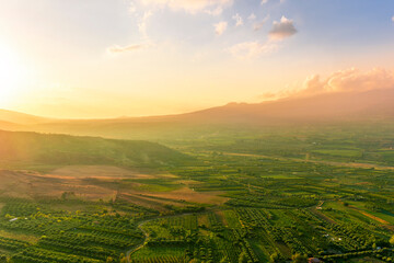 Obraz premium scenic rustic landscape with green hills and farms in a mountain valley during colorful cloudy sunset