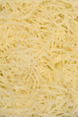 A vibrant, close-up, top-down view showcases a heap of finely grated light yellow cheese, filling the entire frame with its textured strands