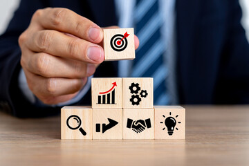 Businessman Building a Strategy with Wooden Blocks Showing Target, Growth, Teamwork, and Innovation