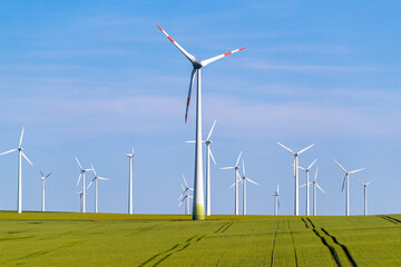 Windräder Windkraftanlagen auf einem grünen Acker vor blauem Himmel