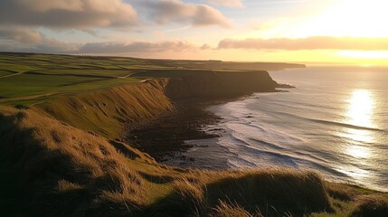 Obraz premium Coastal sunset view; dramatic cliffs meet a calm ocean under a vibrant sky. Golden hour light bathes the scene