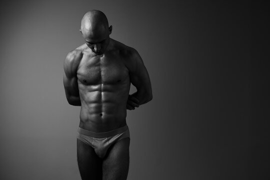 Black and white image of a focused man displaying his sculpted physique, emphasizing strength, determination, and resilience. Ideal for fitness and health themes.