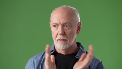 Middle-aged man with a beard wears a blue shirt and displays thoughtful gestures while standing against a green screen backdrop. A moment of contemplation captured.