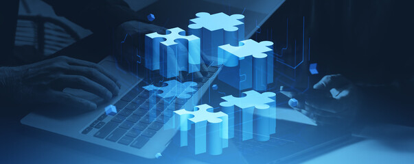 Business hands typing on laptop with glowing puzzle blocks floating in air concept.