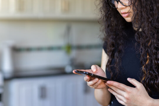 close in image of young person wearing black holding a smartphone with blurry background