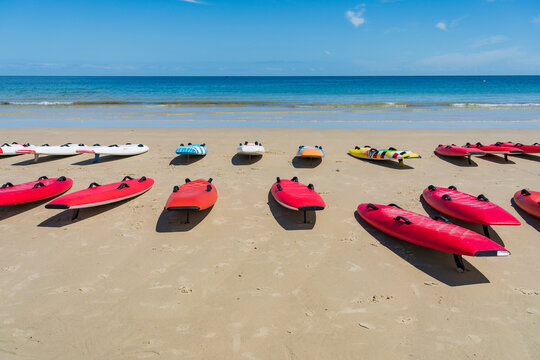 Low angled view of rows of surf skies lined up on a sandy beach