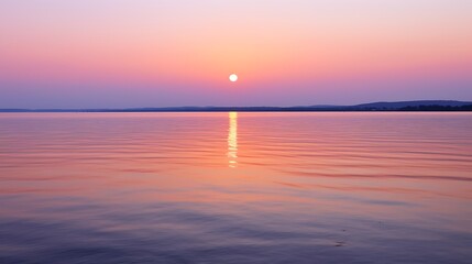 Obraz premium A glowing orange moon rising just above the seaa??s horizon, casting a wide, shimmering golden reflection across calm water, the sky softly transitioning from peach to violet.