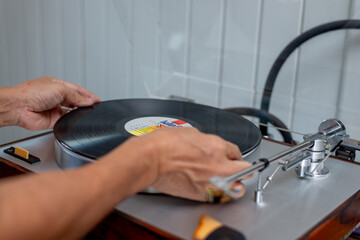 Hand placing vinyl record on vintage turntable