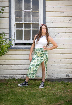 Young adult female posing in front of old window of a country shed