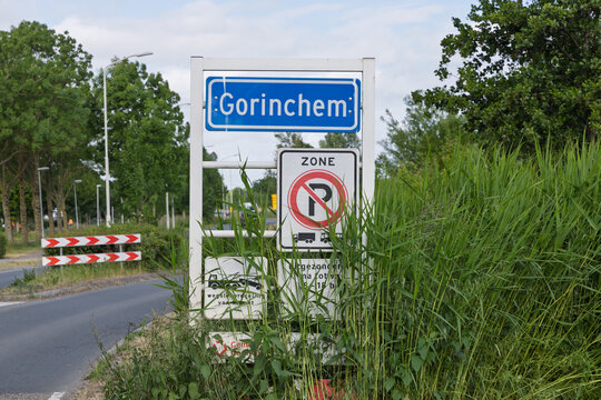 Gorinchem city limits sign in the Netherlands, featuring a "No Parking Zone" for trucks, surrounded by lush green foliage and an overcast sky.