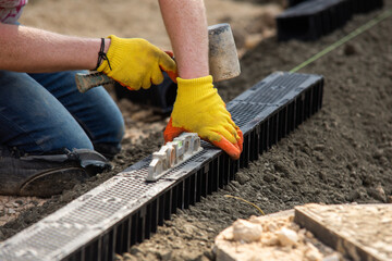 Construction workers installing drainage system channel components at building site