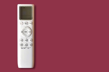 Top view of a white air conditioner remote control with LCD screen, isolated on a maroon background with space for text.