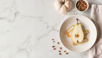 Sliced pear with honey on white plate next to pumpkin and nuts  