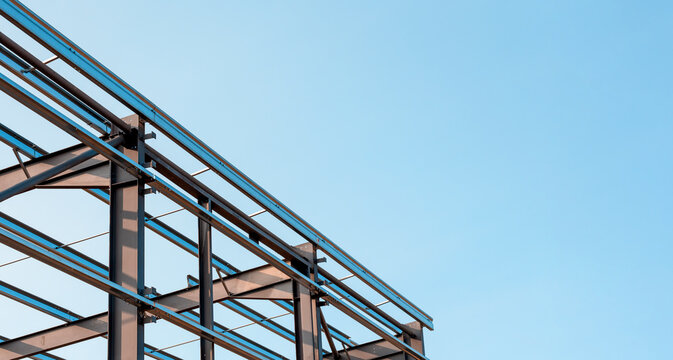 Steel framework of a building under construction against a clear blue sky in bright daylight