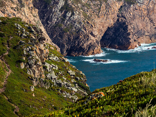Rocks and greenery on a slope with Cabo da Roca in the background, Sintra, Portugal on the Atlantic...