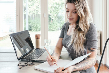 Young woman writing studying at home with pencil and notebook