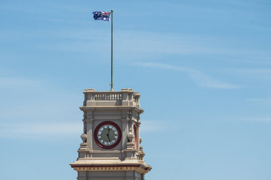 Historic clock tower flying an Australian flag against a blue sky