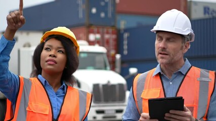Man and Woman Wearing Safety Vests and Hardhats Inspect Shipping Containers at Outdoor Worksite Under Bright Daylight