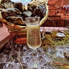 Golden champagne bubbles rise in an elegant flute resting on crushed ice, surrounded by oyster...