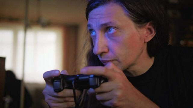 An intensely focused and engaged mood is captured as a man with long hair plays a video game, his gaze fixed on the screen, reflecting deep immersion and concentration