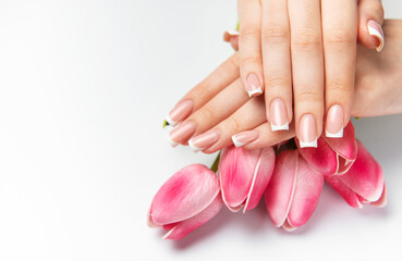 Woman showing french manicure and pink tulips on white background