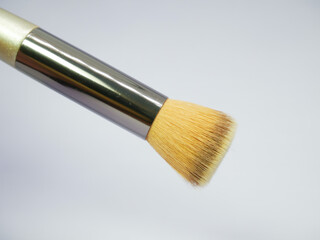 Small round makeup brush with beige residue on white background