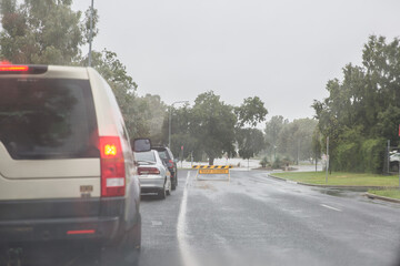 Cars lined up on road with road closed sign due to flooding