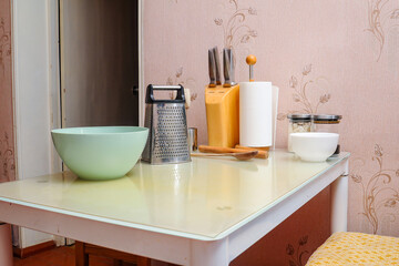 Kitchen scene with various utensils set on a white, glass-topped table, ready for cooking.