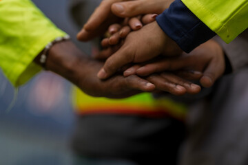 Team logistics workers in high visibility safety gear and hard hats discuss operations at a busy shipping container yard. Team multi nationality working together on site container warehouse.
