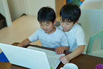 自宅の部屋でパソコンを操作する2人の男の子